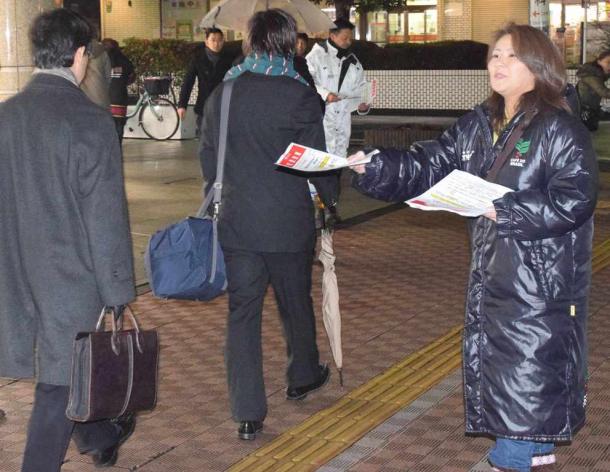 「学校にエアコンを」。駅前でチラシを配る賛成側住民=5日夕、西武線小手指駅
