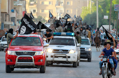 過激派組織「イスラム国」(IS)が「首都」と称するシリア北部ラッカで2014年6月、車列を組んでパレードする戦闘員ら=ロイター