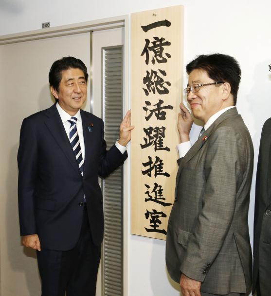 1億総活躍推進室の看板を掛け、笑顔の安倍晋三首相(左)と加藤勝信1億総活躍担当相=2015年10月
