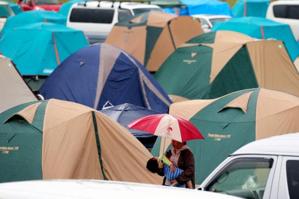 テントが並ぶ避難所で、傘をさして子どもをあやす母親=5月3日、熊本県益城町