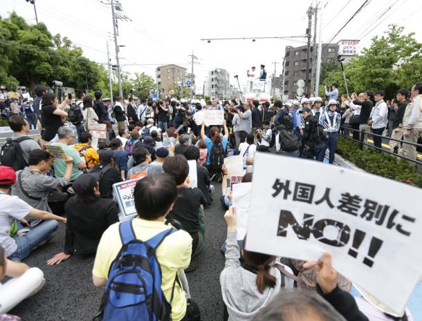 ヘイトスピーチのデモ会場で、デモを阻止しようとプラカードなどを掲げて座り込む人たち=6月5日、川崎市中原区