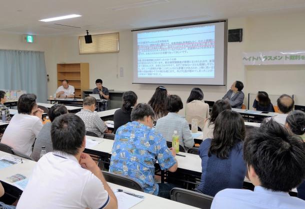 ヘイトハラスメント集会で社内配布された資料を見る人たち=2016年7月23日