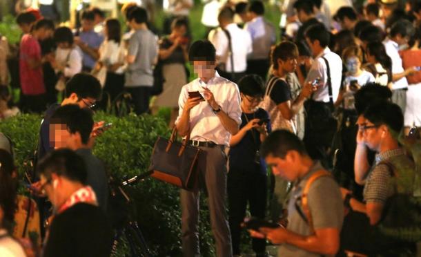 スマホ片手に扇町公園に集まった人たち=29日午後8時12分、大阪市北区