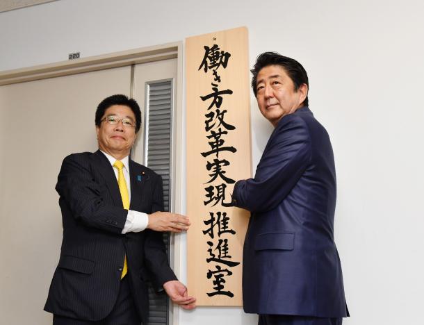 「働き方改革実現推進室」の看板をかかげる安倍晋三首相(右)と加藤勝信・1億総活躍担当相=9月2日、代表撮影