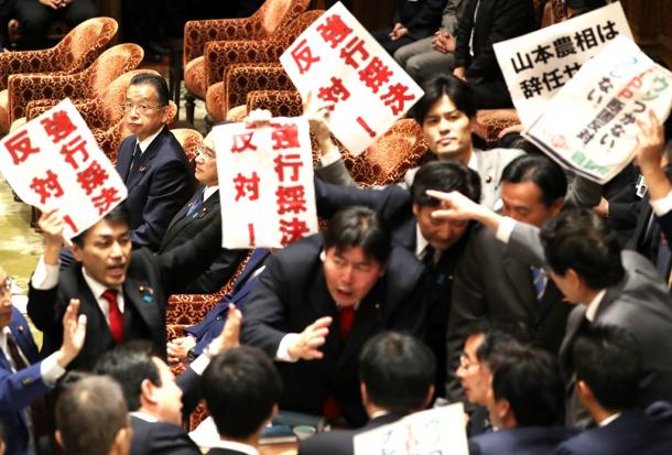 衆院TPP特別委で、採決に反対する野党議員らが詰め寄る委員長席を見る山本有二農水相(左奥)20161104