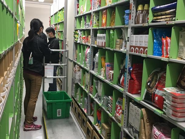 アマゾンの「プライムナウ」向け倉庫。注文された商品を作業員が一つずつ集めていく=東京都内
