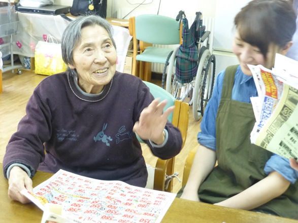 夕食の買い物に行くために、スーパーのチラシを見て職員と相談する認知症の波多野和さん=2016年3月14日、北海道恵庭市