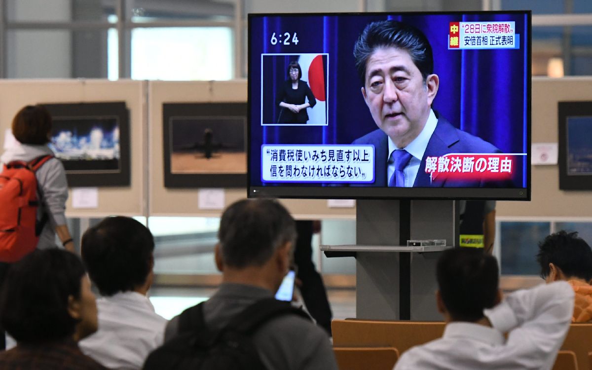 衆院解散を表明する安倍首相のニュースに見入る人たち=25日午後6時11分、福岡市博多区の福岡空港