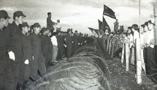 立川基地内民有地収用の測量の警備に出動した警官隊と有刺鉄線のバリケード越しににらみ合う反対派労組員、学生、地元民=1957年7月8日東京都北多摩郡砂川町
