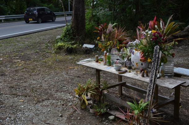 女性が遺棄された現場の献花台には、花やぬいぐるみが供えられていた=16日午前10時9分、沖縄県恩納村