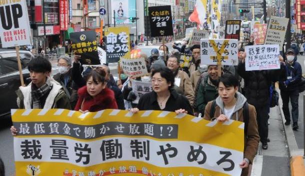 デモの参加者は、テンポの良い音楽のリズムに合わせて「裁量労働制はやめろ」などと声を上げた=2月、東京・JR新宿駅前