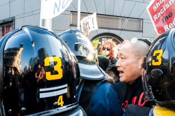 在特会などの極右、排外デモへのカウンター行動。排外主義者のデモ隊へ機動隊に囲まれながら抗議するECDさん=2014年3月16日、東京・池袋(写真家・島崎ろでぃー撮影)