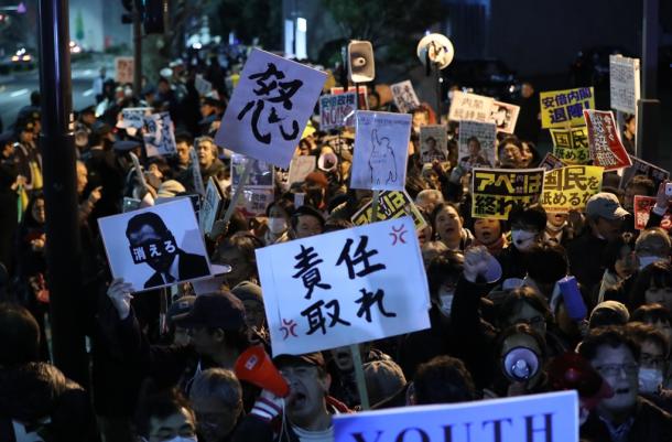 首相官邸前で、抗議のメッセージを掲げる人たち=12日午後8時42分、東京・永田町