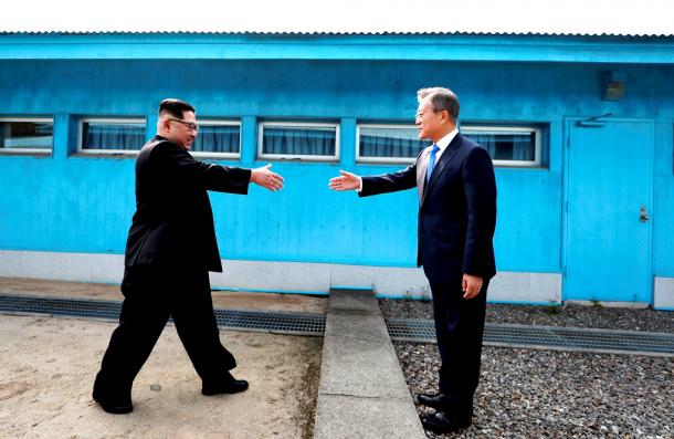 軍事境界線を挟んで握手しようとして手を伸ばす金正恩朝鮮労働党委員長(左)と韓国の文在寅大統領=韓国共同写真記者団撮影.