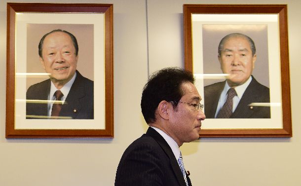 自民党総裁選への不出馬会見の後、退出する岸田文雄政調会長。宏池会出身の宮沢喜一元首相(左)、鈴木善幸元首相の顔写真が壁に飾られていた=2018年7月24日